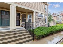 Inviting townhouse entrance with stone accents, lush landscaping, and a welcoming front porch at 23535 E Platte Dr # A, Aurora, CO 80016