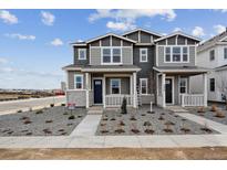 Two-story townhome showcasing gray siding, stone accents, and a neatly landscaped front yard at 1378 Penner Dr, Erie, CO 80026