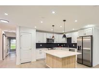 Bright kitchen featuring white cabinets, stainless steel appliances, and a large island with pendant lighting at 10295 E Evans Ave # 114, Aurora, CO 80247