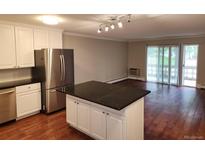 Bright kitchen with an island, stainless steel appliances, and wooden floors that flow into an inviting living space at 9300 E Center Ave # 6A, Denver, CO 80247