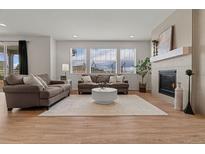 Bright living room with a fireplace, hardwood floors, neutral paint, and plentiful natural light from the large windows at 27307 E Costilla Pl, Aurora, CO 80016