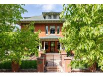 Charming brick two-story home with a landscaped front yard, gated entrance and covered front porch at 1275 N Franklin St, Denver, CO 80218