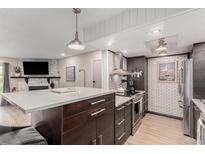 Modern kitchen open to the living room features stainless steel appliances and a large island with seating at 8335 Fairmount Dr # 10-208, Denver, CO 80247