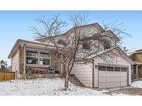 Charming two-story home with attached garage, covered porch, and snow-covered yard at 6366 Nassau Ct, Highlands Ranch, CO 80130