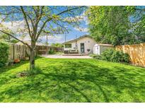 Expansive backyard featuring a well-maintained lawn, patio seating, and privacy fence at 3625 W 9Th Ave, Denver, CO 80204
