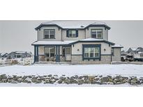 Charming two-story home featuring classic architectural elements and complemented by snowy front yard landscaping at 9904 E 161St Pl, Brighton, CO 80602