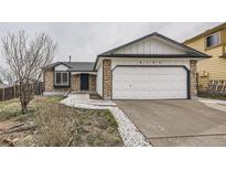Charming home featuring stone accents, white siding, and a two-car garage, all under an overcast sky at 6102 S Owens Ct, Littleton, CO 80127