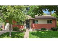 Charming brick home featuring a well-manicured lawn, a flower-adorned entrance, and a welcoming wreath on the door at 6371 Brooks Dr, Arvada, CO 80004