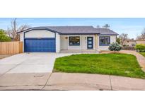 Charming ranch home featuring a blue garage door and trim, a well-manicured lawn, and freshly painted white brick at 2484 E 101St Ct, Thornton, CO 80229