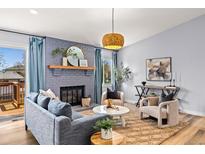 Cozy living room with stylish blue sofa, fireplace, and a large window with natural light at 2484 E 101St Ct, Thornton, CO 80229