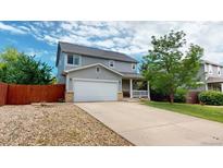 Charming two-story home featuring a well-maintained lawn, a two car garage, and a cozy front porch at 2160 Ance St, Strasburg, CO 80136