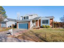 Charming two-story home featuring a blue garage door, brick accents, and a well-maintained front yard at 19697 E Flora Pl, Aurora, CO 80013