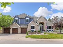 Beautiful two story home featuring a brick and blue exterior, three car garage, and manicured front lawn at 2555 S Zang St, Denver, CO 80228