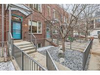 Charming brick townhouse featuring a lovely landscaped front entry and a bright blue front door at 4575 Tennyson St # 104, Denver, CO 80212