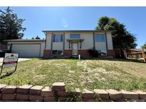 Split level home with neutral paint, brick accents and a nicely maintained lawn at 8127 Lafayette St, Denver, CO 80229