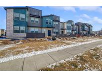 Modern townhouses with gray and teal exterior, private fenced yards, and a sidewalk at 4758 Kittredge St # 2, Denver, CO 80239
