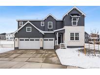 Two-story craftsman home with gray and white exterior, two car garage, and snowy front yard at 5723 Farrier Pt, Castle Rock, CO 80104