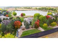 Stunning aerial view of a lakeside home with mature trees in vibrant fall colors and a long private driveway at 10667 E Goose Haven Dr, Lafayette, CO 80026