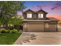 Inviting two-story home featuring a stone facade, attached garage, and manicured lawn at 9650 Raven St, Firestone, CO 80504
