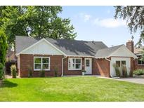 Charming brick home with a well-manicured lawn, lovely landscaping, and eye-catching architectural details at 2635 Kearney St, Denver, CO 80207