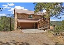 Charming stone house with a metal roof, a two-car garage, and wooden fence at 77 Krestview Ln, Golden, CO 80401