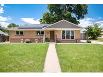 Charming brick home with a well-manicured lawn, inviting walkway, and solar panels, perfect for sustainable living at 585 Estes St, Lakewood, CO 80226