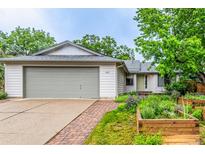 Charming home with a large front yard featuring raised garden beds and a brick walkway to the front door at 182 Lois Cir, Louisville, CO 80027
