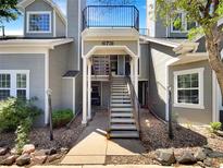 Inviting gray condo with stairway entrance and second-story balcony, enhanced by manicured landscaping and natural light at 6731 S Ivy Way # B4, Centennial, CO 80112