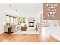 Bright living room features hardwood floors, a cozy fireplace, and natural light from large windows at 6535 Balsam St, Arvada, CO 80004