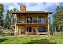 Charming home with a stone chimney, covered patio, and a balcony perfect for enjoying the outdoors at 1555 Three Peaks Rd, Golden, CO 80403