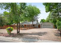 Charming home featuring a spacious front yard, complemented by a detached garage and inviting wooden fence at 6031 S Pennsylvania St, Centennial, CO 80121