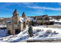 Castle-style home on a snow-covered lot with a large driveway at 3120 Bears Den Dr, Sedalia, CO 80135