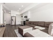 Open-concept living room with modern appliances, white cabinets, and a cozy brown sectional sofa at 2876 W 53Rd Ave # 111, Denver, CO 80221