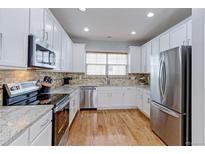 Bright kitchen features stainless steel appliances, granite countertops, wood floors and tile backsplash at 14214 Lakeview Ln, Broomfield, CO 80023