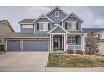 Charming two-story home features a well-maintained lawn and a three-car garage, with classic blue siding at 10551 Redcone Way, Highlands Ranch, CO 80130