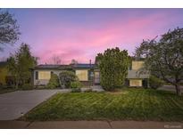 Charming home with lush landscaping, solar panels, and a large front yard under a beautiful sunset sky at 13661 W Tufts Ave, Morrison, CO 80465