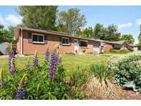 Charming red brick home with a lush, green front yard and mature landscaping and flower beds at 6314 Brooks Dr, Arvada, CO 80004