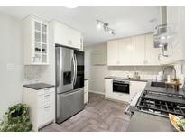 Modern kitchen with stainless steel appliances, white cabinets, and gray countertops offers a stylish cooking space at 6314 Brooks Dr, Arvada, CO 80004