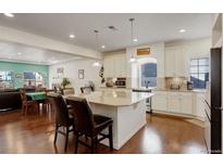 Bright kitchen featuring a large island, white cabinets, granite countertops, and modern stainless steel appliances at 10777 Wheeling Dr, Commerce City, CO 80022