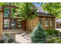 Charming brick home featuring a front door with sidelights and detailed front yard landscaping at 10886 E Crestline Cir, Englewood, CO 80111