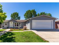 Charming single-story home with gray siding, manicured lawn and a two car garage at 205 Spruce Ave, Lochbuie, CO 80603