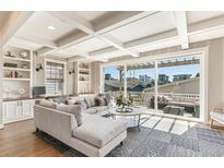 Spacious living room with large windows, coffered ceilings, built-in shelving, and access to an outdoor patio at 5880 Beeler Ct, Denver, CO 80238
