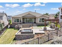 Beautifully landscaped backyard with stone patio, fire pit, and pergola, perfect for outdoor entertaining at 27381 E Lakeview Dr, Aurora, CO 80016