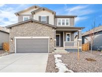 Two-story house with stone and siding exterior, gray garage door, and a small front porch at 13402 E 110Th Way, Commerce City, CO 80022