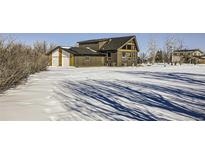 A remodeled home with a large backyard, snow-covered lawn, and attached garage at 4022 Arleigh Dr, Berthoud, CO 80513