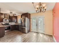 This spacious kitchen features stainless steel appliances, dark cabinetry and an adjacent dining area at 3659 W Union Ave, Denver, CO 80236