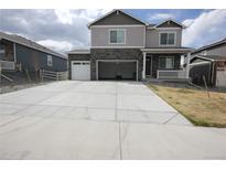 Two-story home featuring a large concrete driveway and an attached garage with a stone and light gray facade at 4955 Trails Edge Ln, Castle Rock, CO 80104
