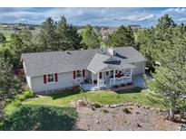 Charming single-story home featuring a cozy front porch, vibrant red shutters, and surrounded by mature trees at 36921 Ruger Ct, Elizabeth, CO 80107