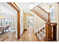 Hallway with hardwood floors and wooden staircase featuring a colorful runner, connecting different areas of the home at 677 N Gilpin St, Denver, CO 80218