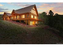 Stunning log cabin featuring a wrap-around deck and stone pathway at 9868 Overlook Rd, Sedalia, CO 80135